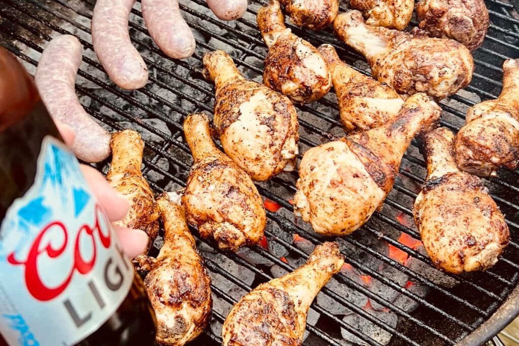 chicken legs and brats on a charcoal grill