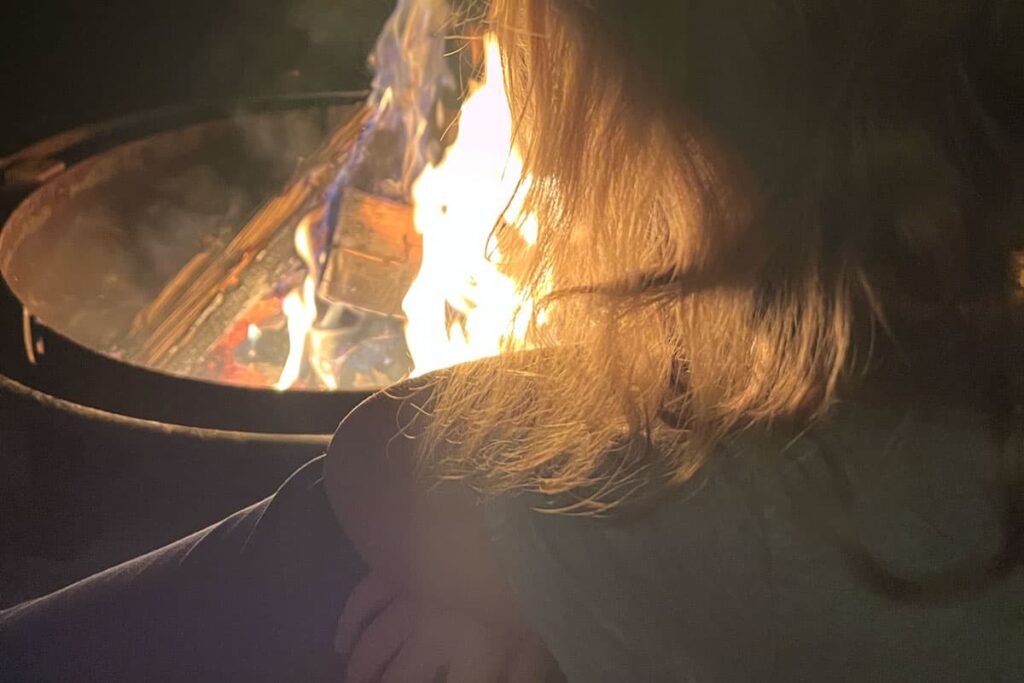 child watching a backyard fire pit with dad